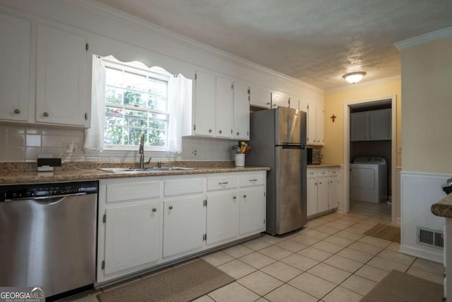 kitchen featuring crown molding, washer / clothes dryer, appliances with stainless steel finishes, white cabinets, and a sink