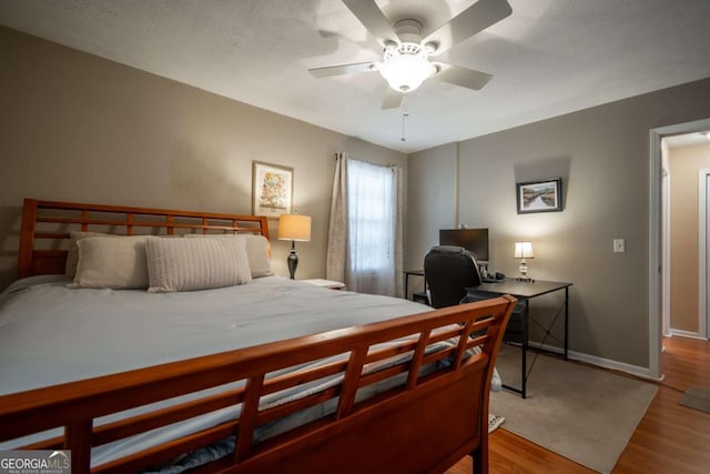 bedroom with a ceiling fan, baseboards, and wood finished floors