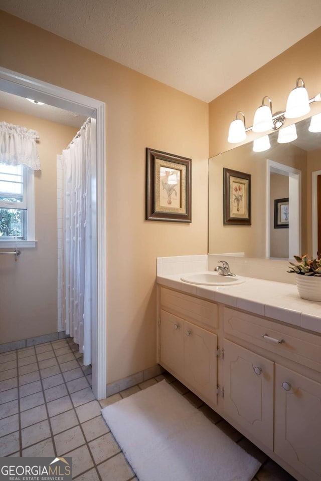 bathroom featuring a textured ceiling, tile patterned flooring, vanity, baseboards, and a shower with curtain