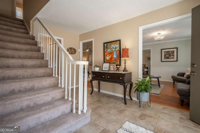 stairway with ornamental molding, baseboards, and tile patterned floors