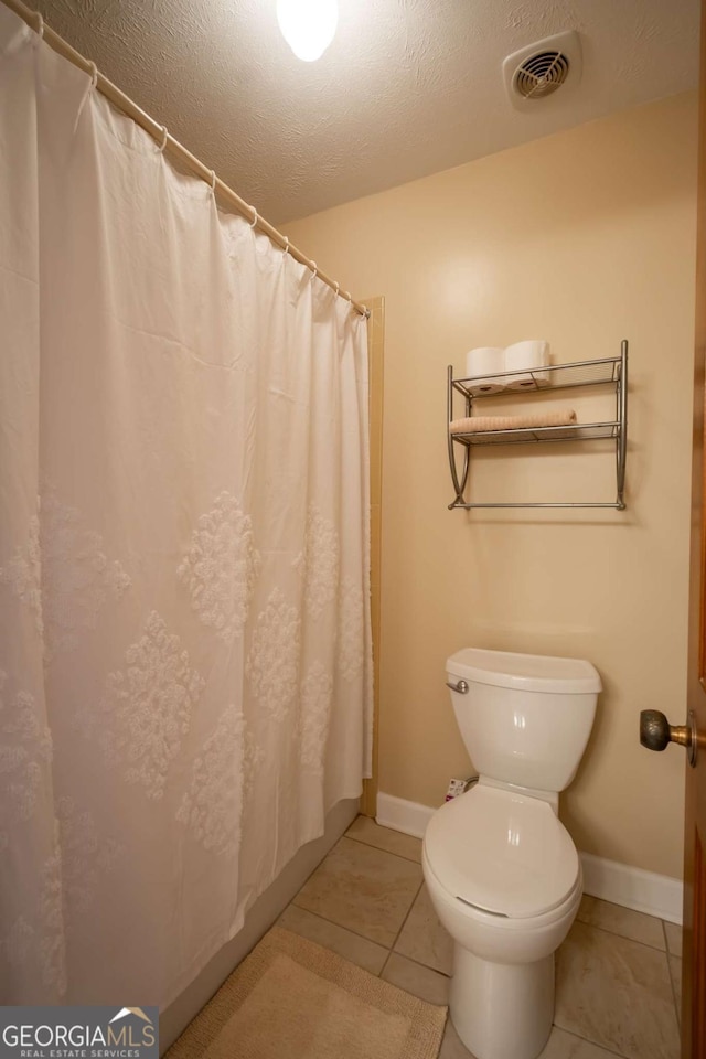 full bath with visible vents, toilet, a textured ceiling, tile patterned flooring, and baseboards