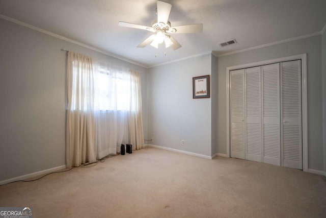 unfurnished bedroom featuring light colored carpet, visible vents, baseboards, ornamental molding, and a closet