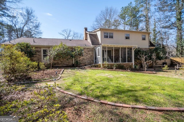 back of house featuring a sunroom, brick siding, a yard, and a chimney