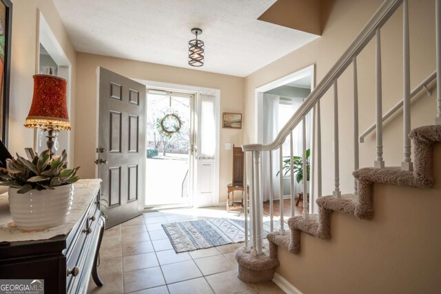 entryway with light tile patterned floors, baseboards, and stairway