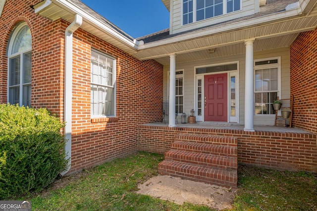 property entrance with a porch and brick siding