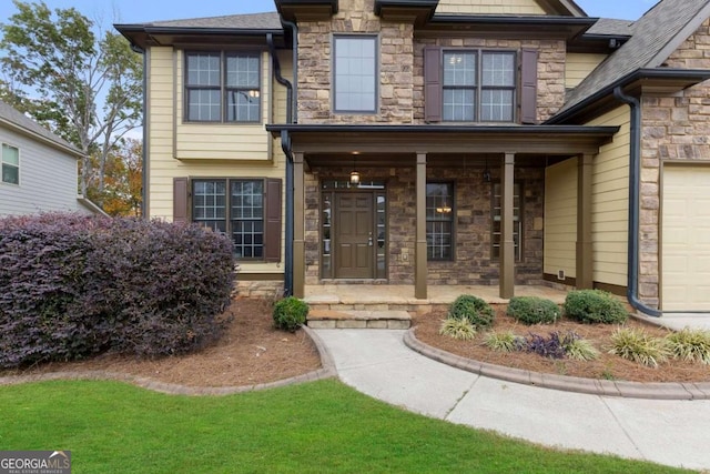 property entrance with an attached garage, stone siding, and covered porch