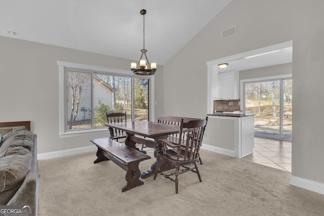 dining room with a healthy amount of sunlight, visible vents, a chandelier, and light carpet