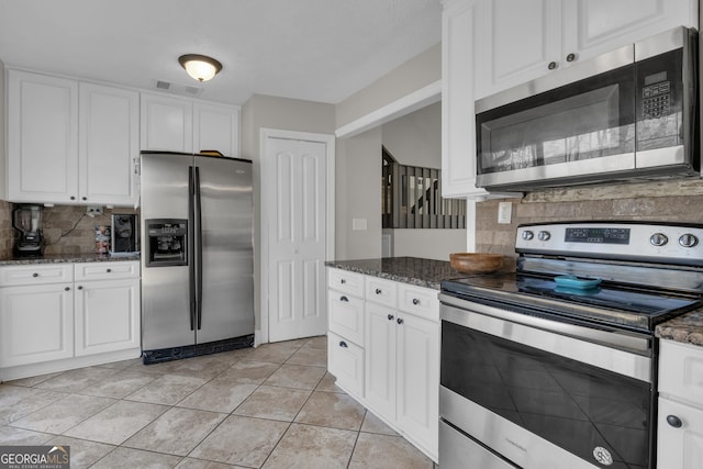 kitchen featuring stainless steel appliances, visible vents, white cabinets, and dark stone counters