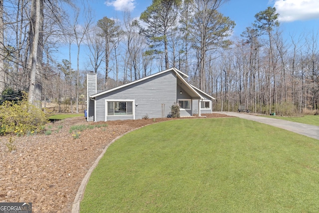 view of front of property with a front lawn, driveway, and a chimney