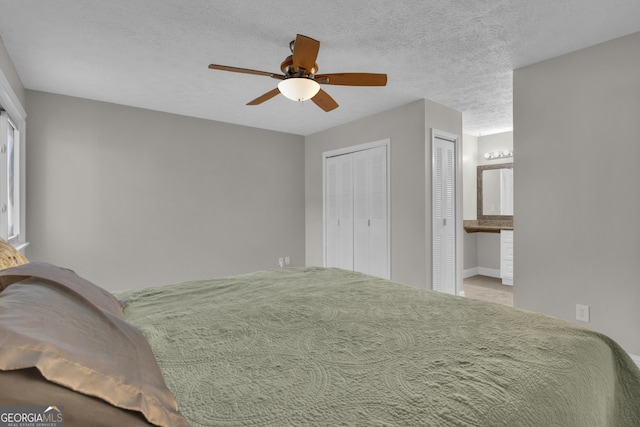 bedroom with two closets, connected bathroom, a textured ceiling, and a ceiling fan