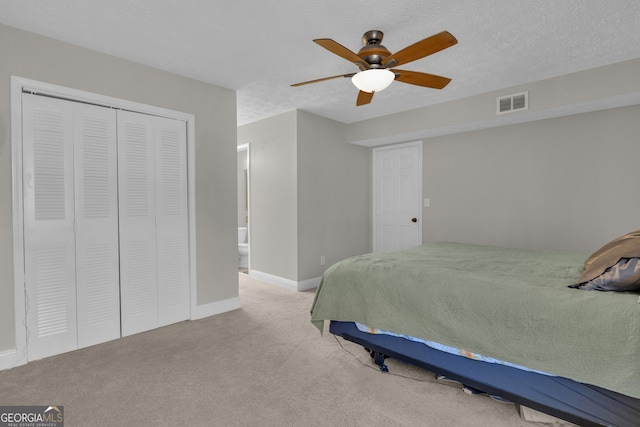 carpeted bedroom with visible vents, a textured ceiling, a closet, baseboards, and ceiling fan