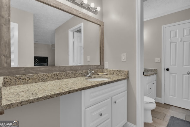 bathroom with tile patterned flooring, baseboards, toilet, vanity, and a textured ceiling