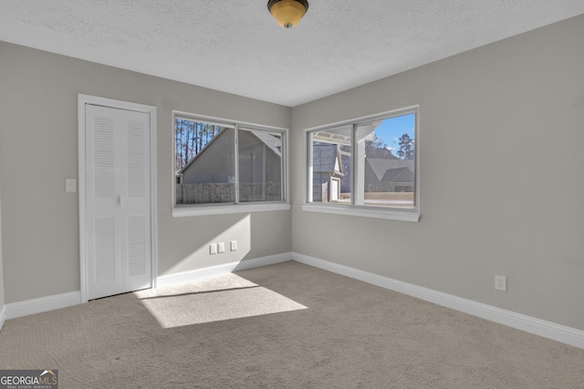 unfurnished room featuring carpet, baseboards, and a textured ceiling