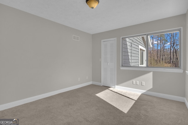 unfurnished bedroom featuring visible vents, a textured ceiling, a closet, carpet, and baseboards