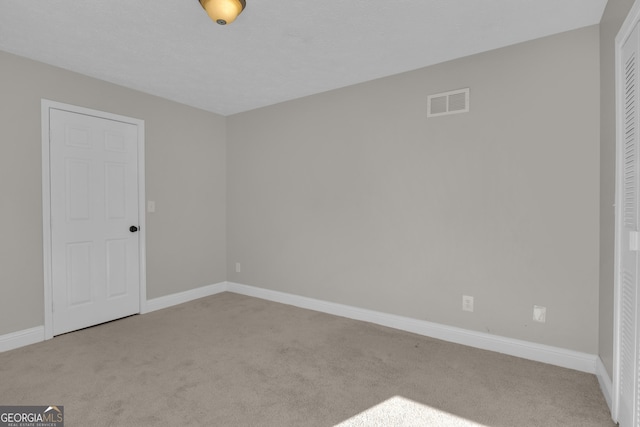 carpeted spare room featuring baseboards and visible vents