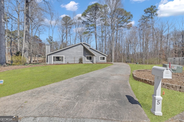 view of property exterior with a lawn, driveway, and a chimney