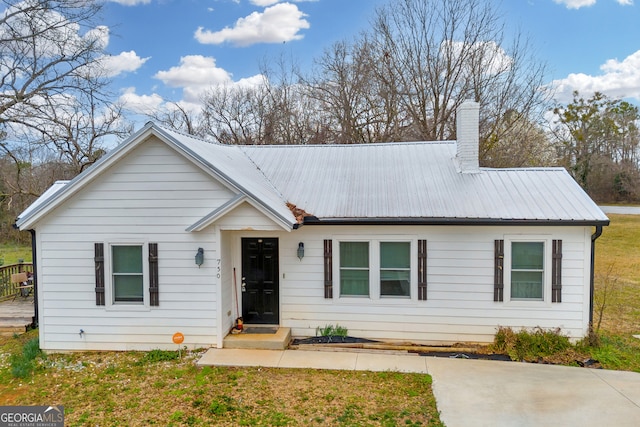 single story home with a chimney, a front lawn, and metal roof