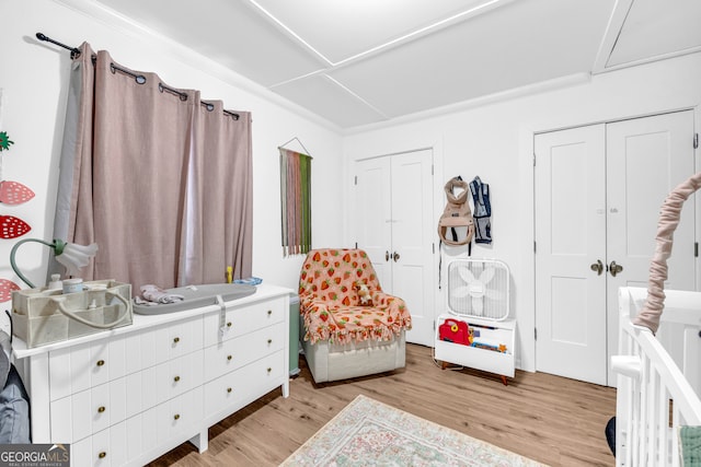 bedroom with multiple closets and light wood-type flooring