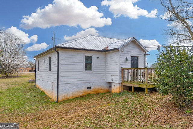 back of house featuring crawl space, a yard, a wooden deck, and metal roof