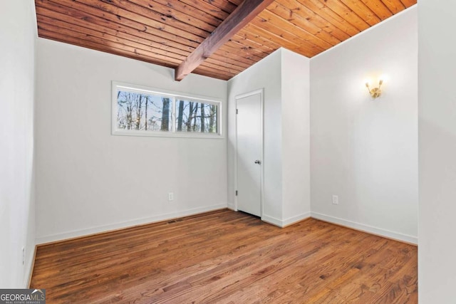 empty room with wooden ceiling, lofted ceiling with beams, baseboards, and wood finished floors