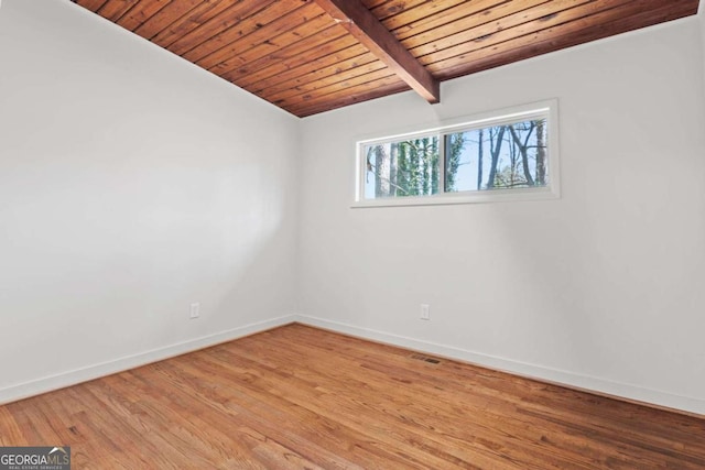 empty room featuring vaulted ceiling with beams, wooden ceiling, light wood-style flooring, and baseboards