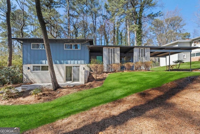 rear view of house with board and batten siding, a lawn, and brick siding