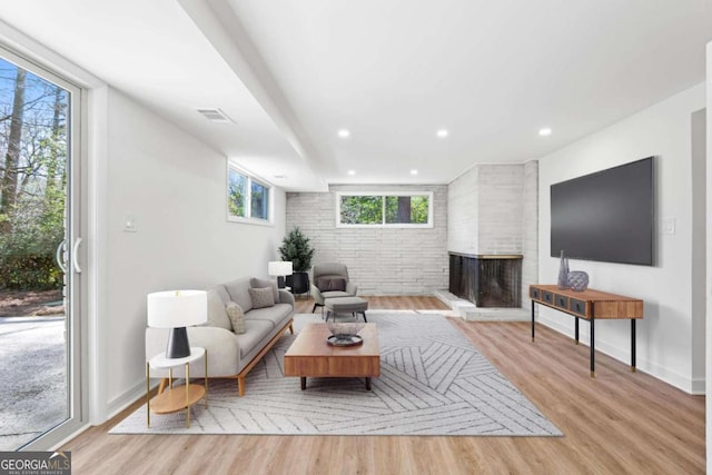 living room with recessed lighting, wood finished floors, visible vents, and a multi sided fireplace