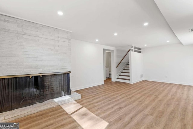 unfurnished living room with a fireplace, recessed lighting, light wood-type flooring, baseboards, and stairs