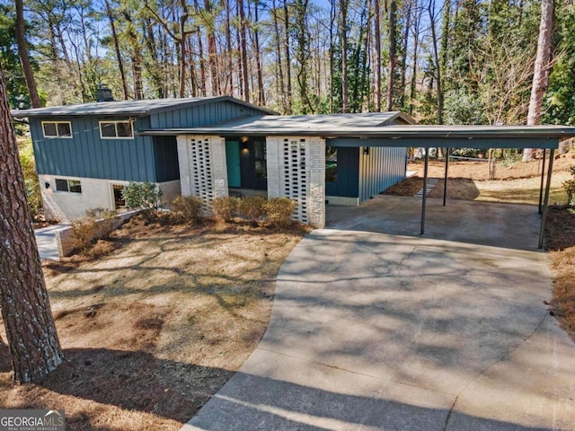 view of front facade featuring driveway, brick siding, and a chimney