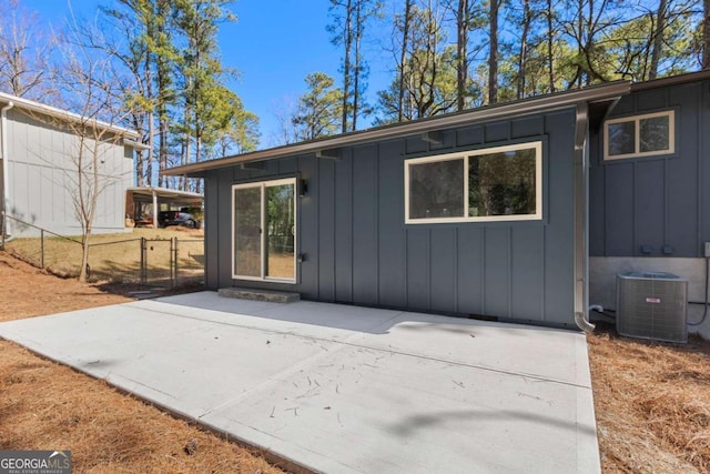 back of property featuring board and batten siding, a patio area, cooling unit, and fence