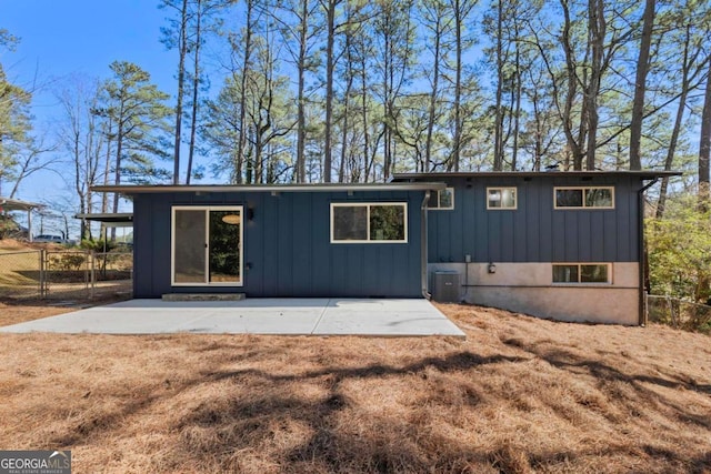 rear view of house with board and batten siding, cooling unit, a patio area, and fence