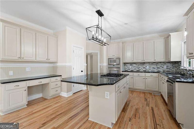 kitchen with stainless steel appliances, a kitchen island, a sink, light wood-type flooring, and built in desk