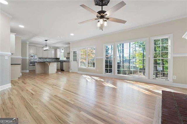 unfurnished living room with a ceiling fan, recessed lighting, crown molding, and light wood finished floors
