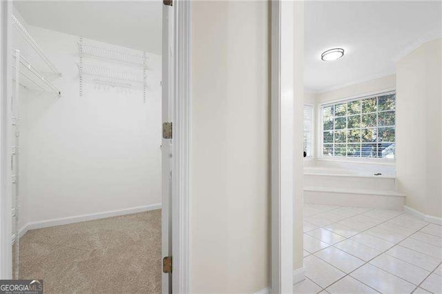 bathroom with ornamental molding, a bathing tub, baseboards, and tile patterned floors