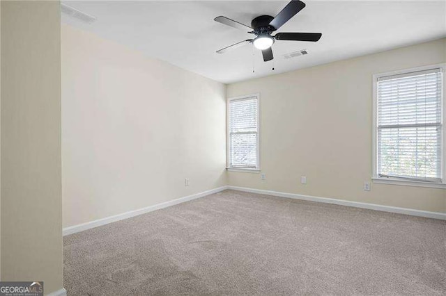spare room featuring carpet floors, visible vents, baseboards, and ceiling fan
