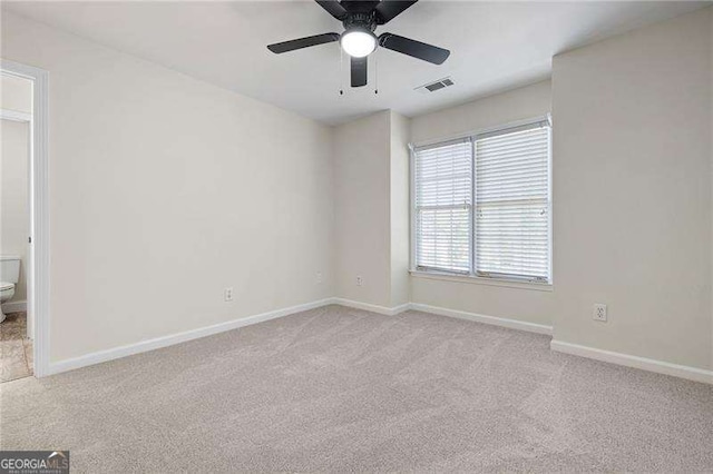 carpeted spare room with baseboards, visible vents, and a ceiling fan