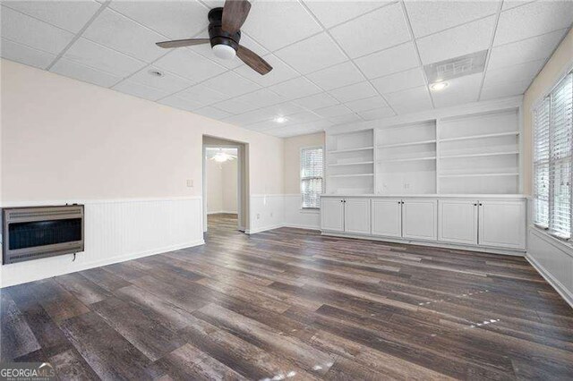 unfurnished living room featuring dark wood-style floors, a wealth of natural light, and heating unit