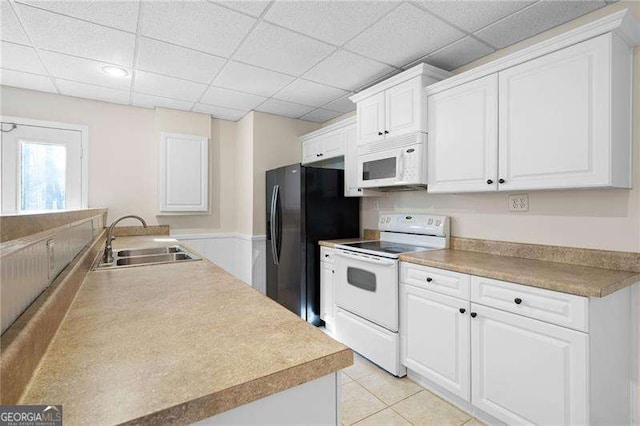 kitchen with a paneled ceiling, white appliances, white cabinets, and a sink
