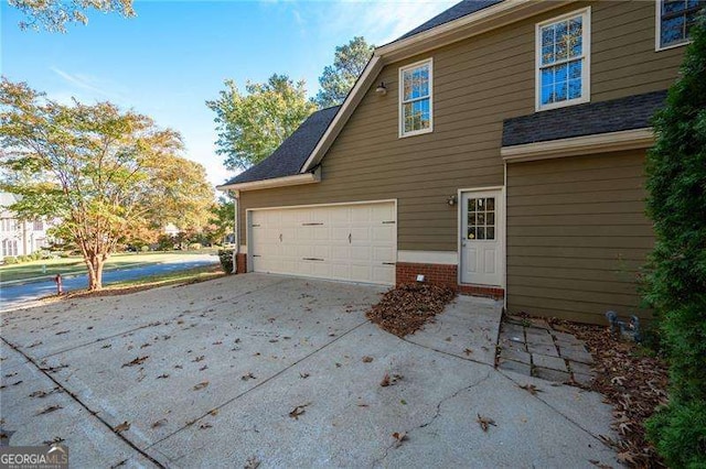 view of home's exterior with an attached garage, concrete driveway, and brick siding