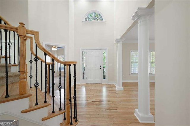 entryway with plenty of natural light, stairway, light wood-type flooring, and ornate columns