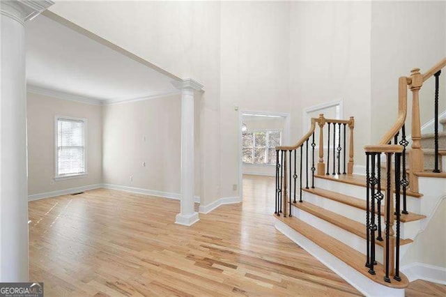 stairs featuring ornamental molding, wood finished floors, decorative columns, and baseboards