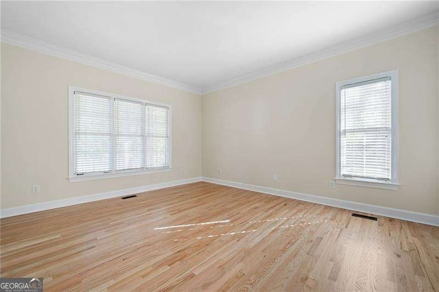 empty room with a healthy amount of sunlight, visible vents, and crown molding