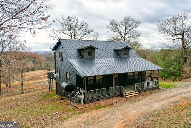 view of front facade featuring driveway, covered porch, metal roof, and heating fuel