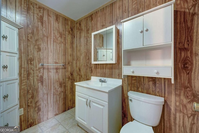 half bath featuring toilet, wood walls, tile patterned floors, and vanity