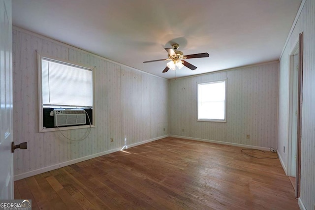 spare room with baseboards, a ceiling fan, wood finished floors, crown molding, and cooling unit