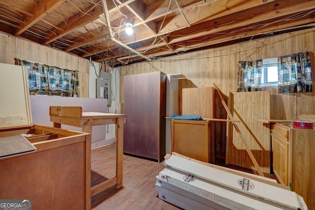 basement featuring wood finished floors, electric panel, and wooden walls