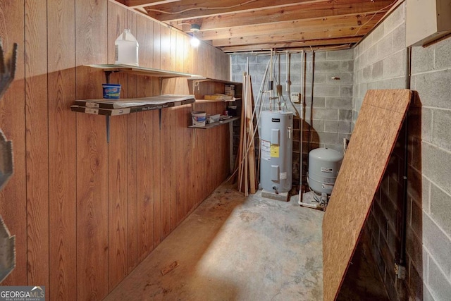 unfinished basement with concrete block wall, electric water heater, and a bar