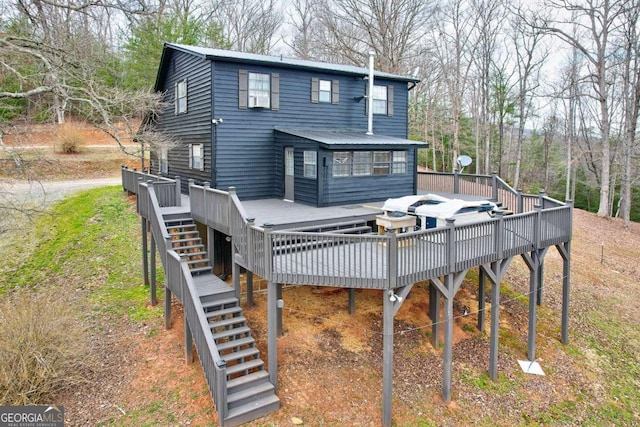 back of house featuring a hot tub, a deck, and stairs