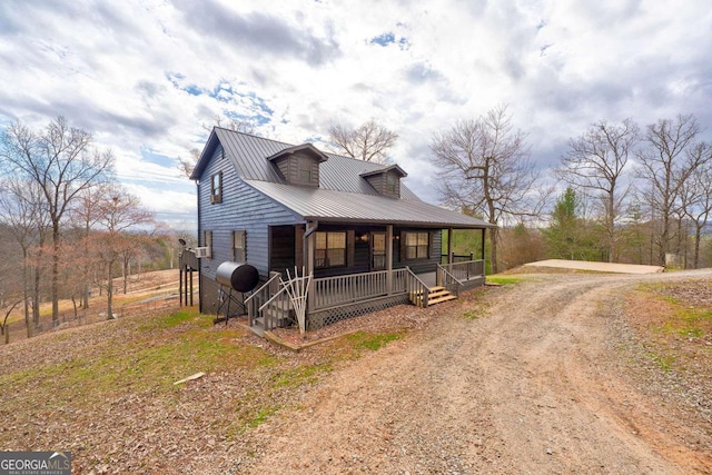 rustic home featuring driveway, metal roof, and a porch