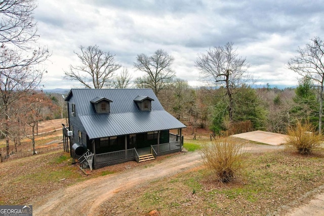 view of front of home featuring covered porch, driveway, heating fuel, and metal roof